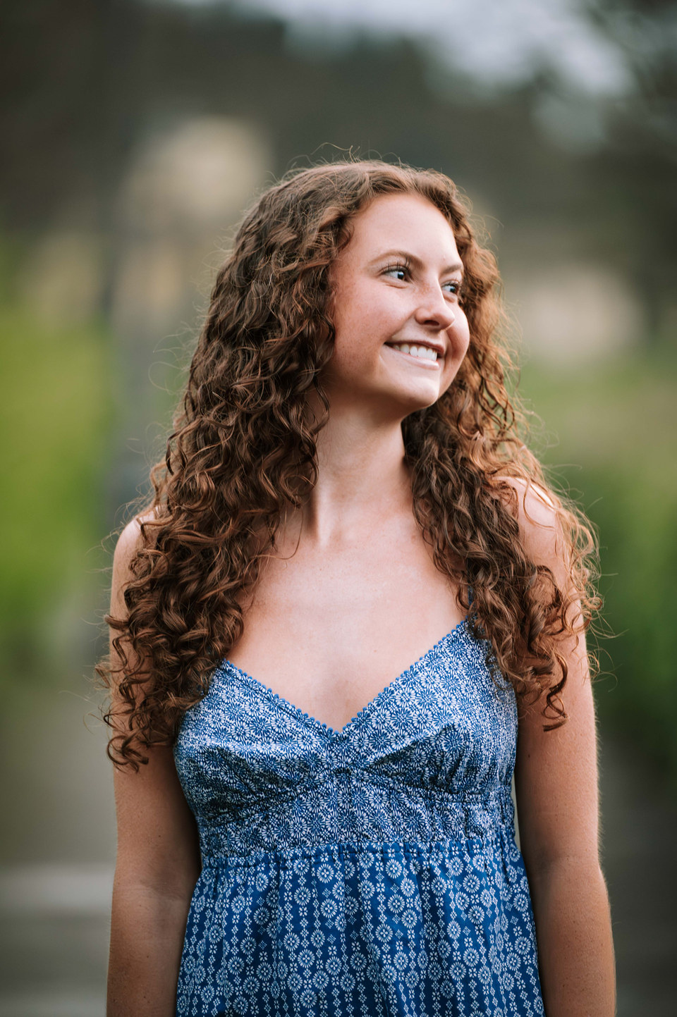 Portrait of a smiling woman with curly hair in a blue summer dress