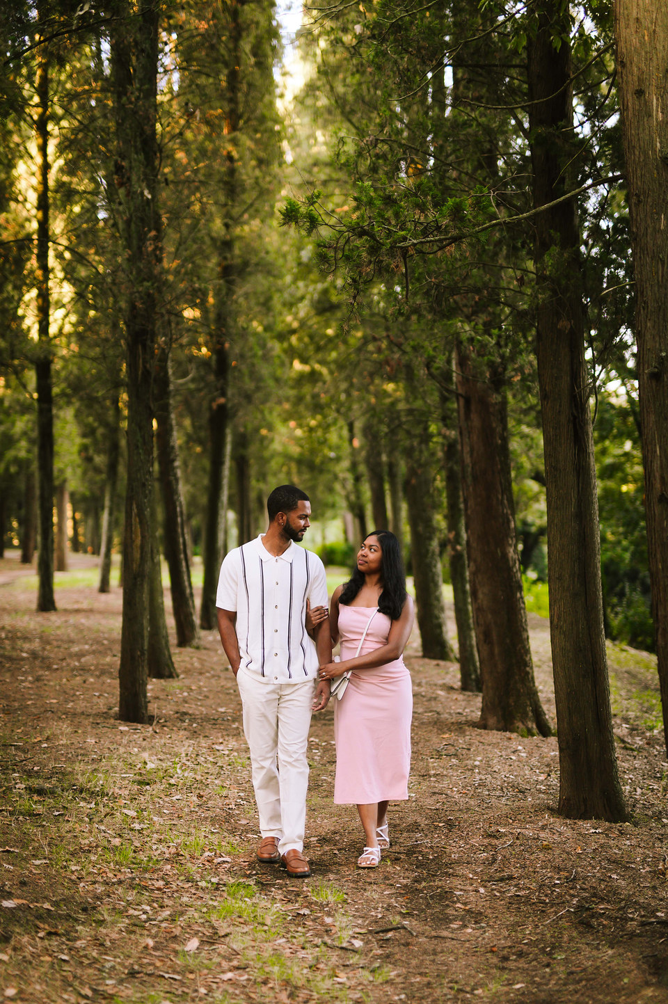 Couple walking hand in hand along a tree-lined path in a Florence garden