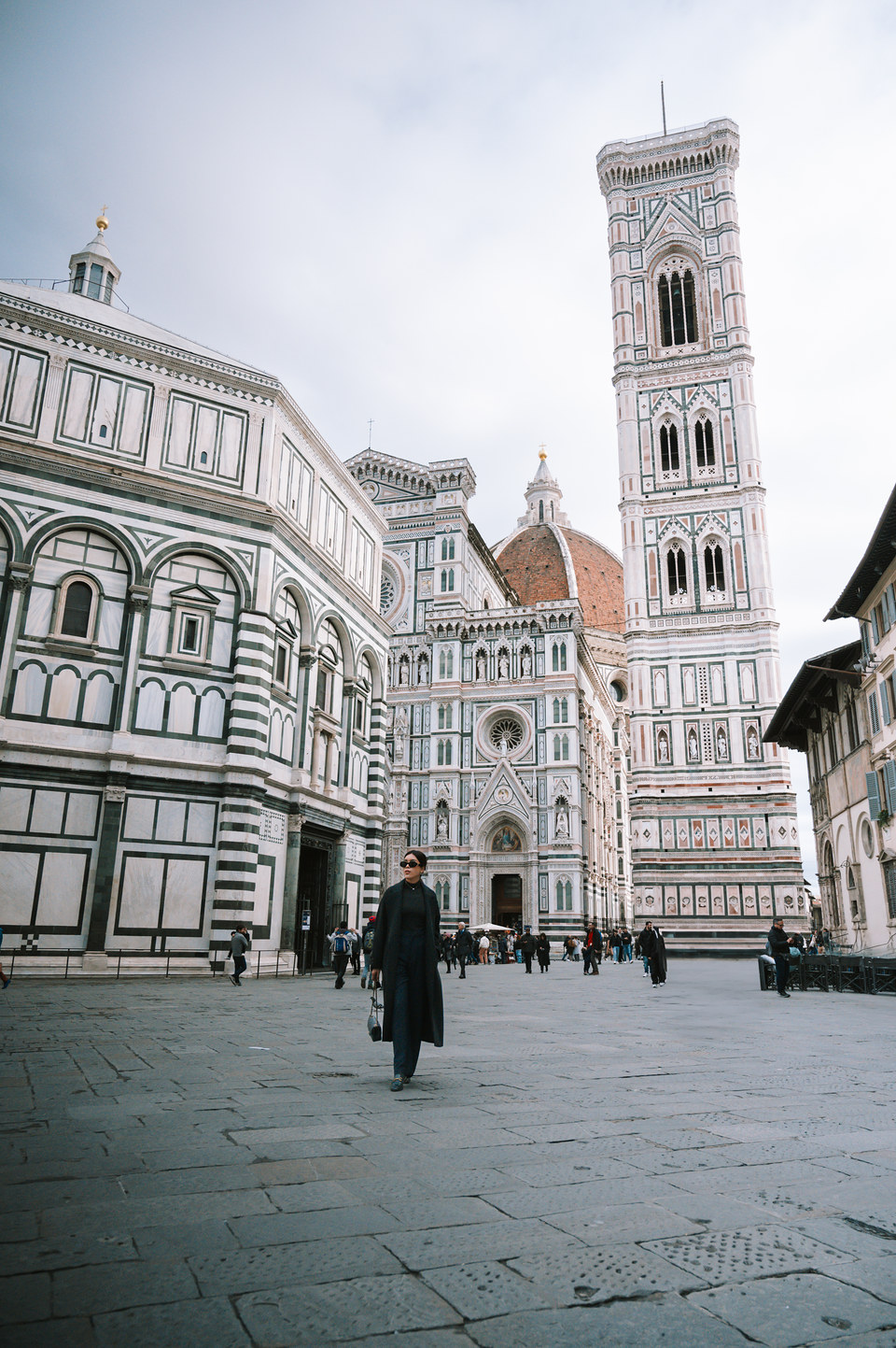 Woman walking across Piazza del Duomo, with the Baptistery, the cathedral and Giotto's bell tower